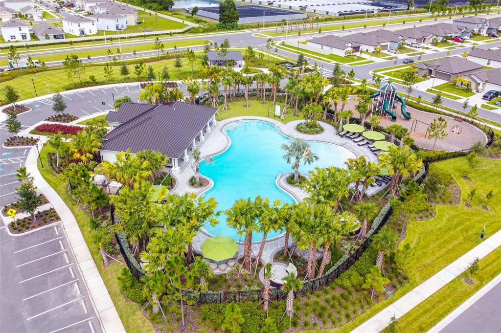 An aerial view of a community swimming pool, clubhouse, playground, and parking lot — 2925 BERRY COPPICE PLACE, WIMAUMA, FL