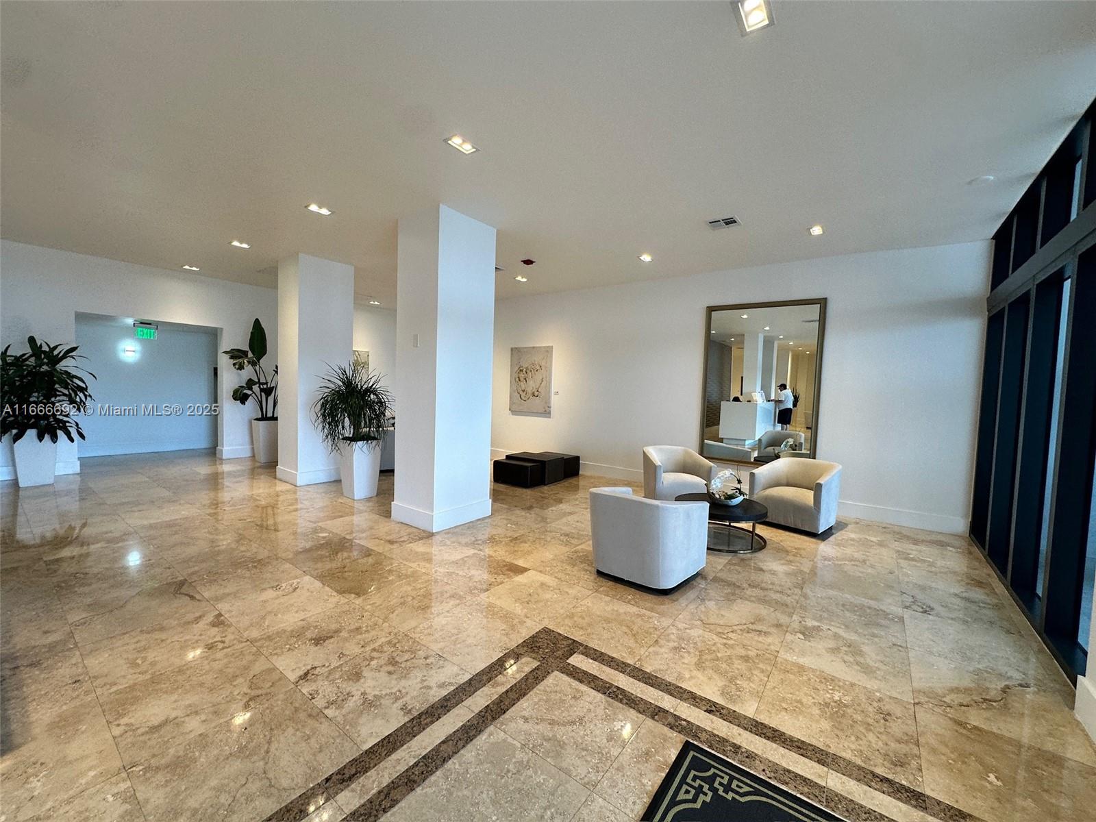 A spacious lobby features polished stone floors, white columns, seating areas, and a large mirror — 2201 S Ocean Dr # 904, Hollywood FL 33019, HOLLYWOOD, FL