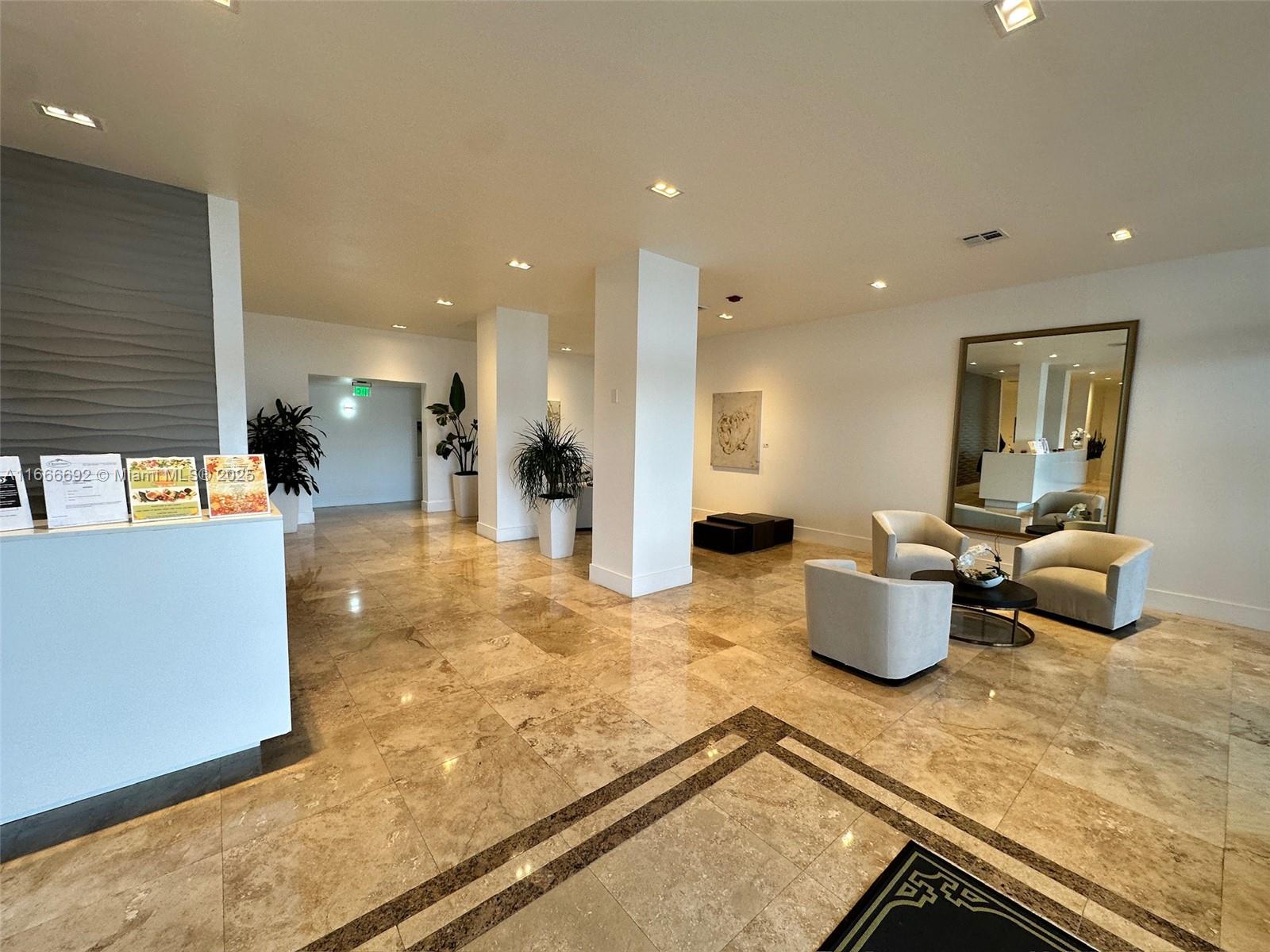 A spacious lobby features marble tile flooring, white pillars, seating areas, and a large mirror — 2201 S Ocean Dr # 904, Hollywood FL 33019, HOLLYWOOD, FL