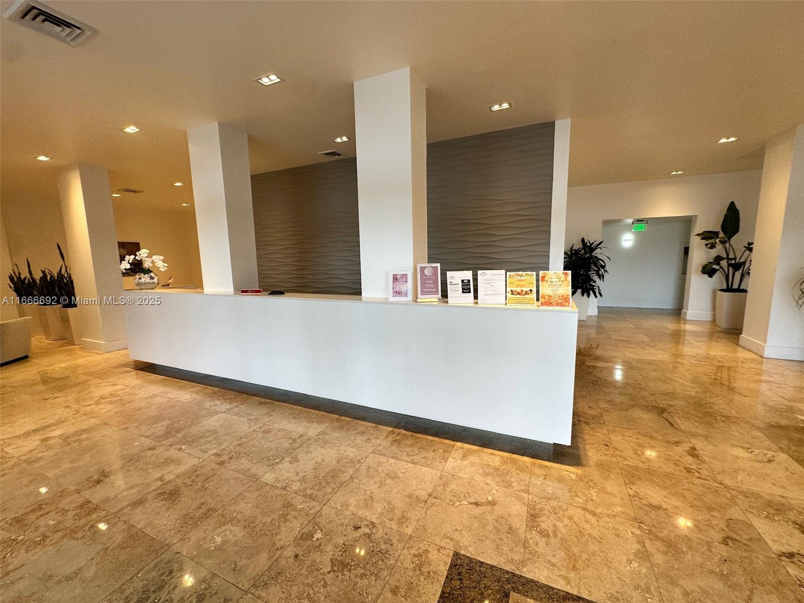 A modern lobby features a long white reception desk, marble flooring, and textured accent walls — 2201 S Ocean Dr # 904, Hollywood FL 33019, HOLLYWOOD, FL