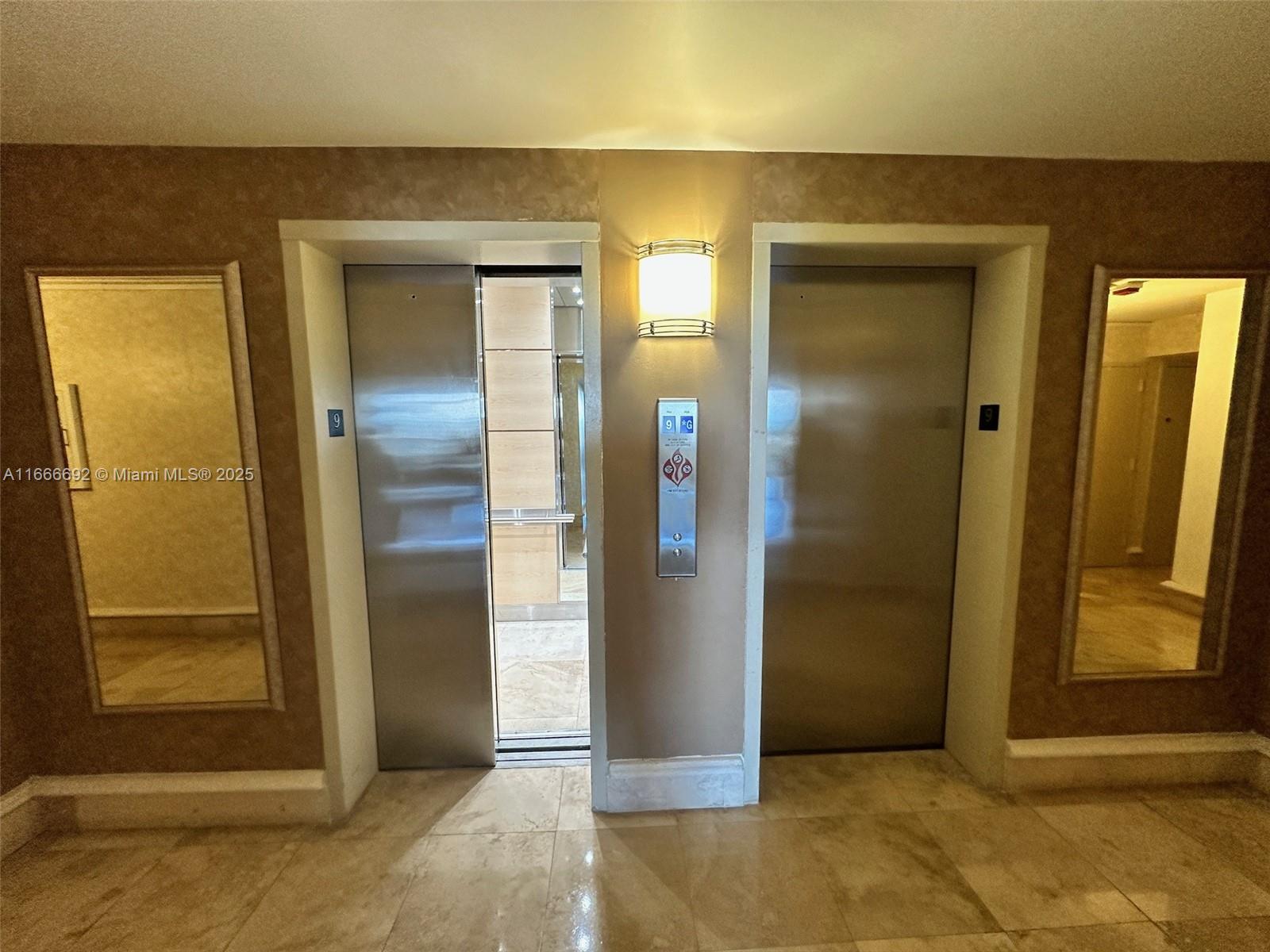 An elevator lobby features two stainless steel doors, a central control panel, and wall mirrors — 2201 S Ocean Dr # 904, Hollywood FL 33019, HOLLYWOOD, FL