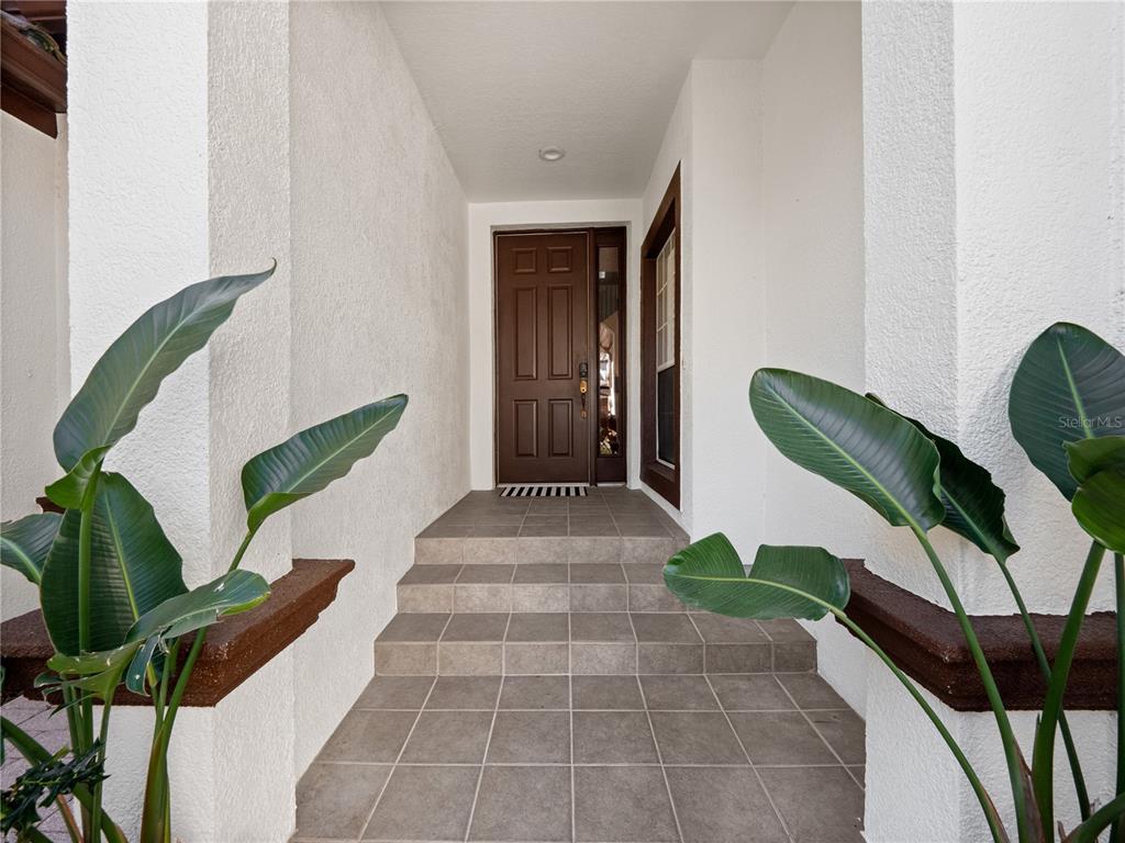 A brown front door is reached by three tiled steps in a covered entryway — 8224 TIVOLI DRIVE, ORLANDO, FL