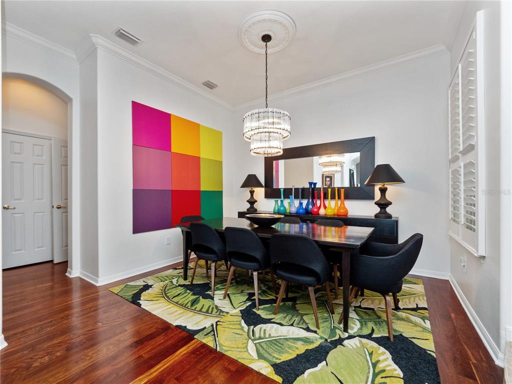 A dining room features a dark wood table, black chairs, a colorful wall art piece, and a rug — 8224 TIVOLI DRIVE, ORLANDO, FL