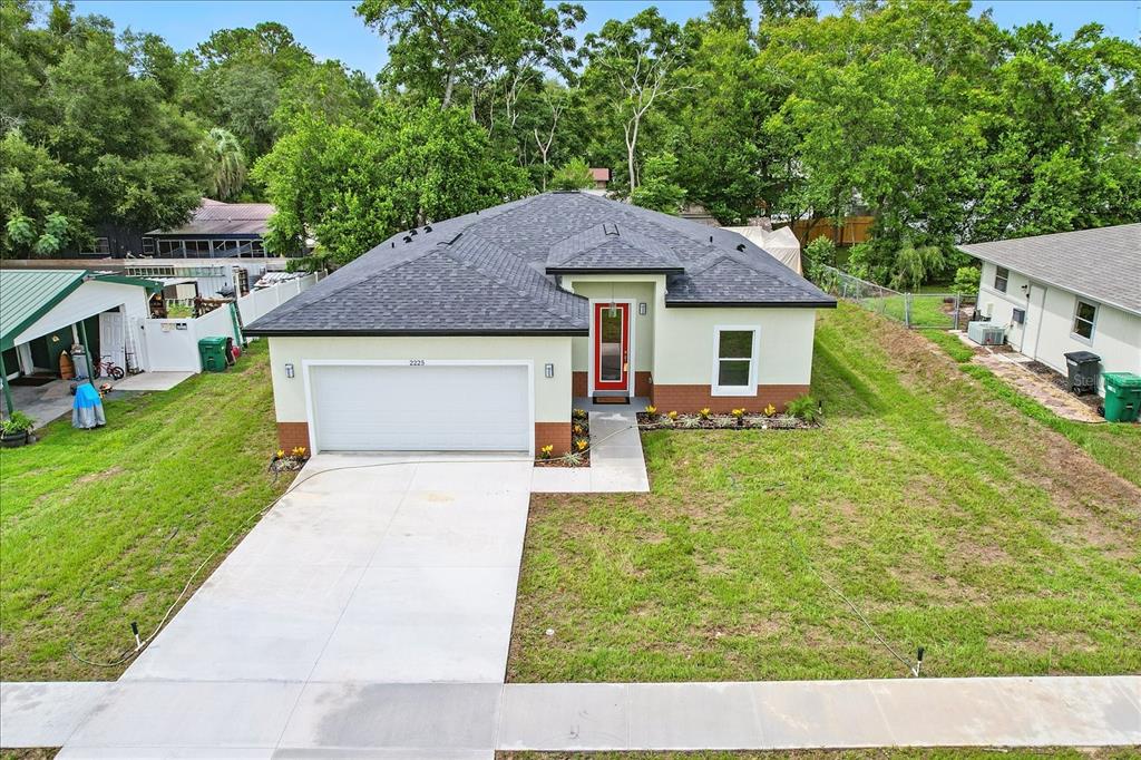 An exterior view of a single-story house with a white garage, red door, and lawn — 2225 W HOWARD PLACE, CITRUS SPRINGS, FL