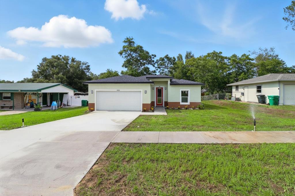 A single-story house with a white garage door, light green siding, and a red front door — 2225 W HOWARD PLACE, CITRUS SPRINGS, FL
