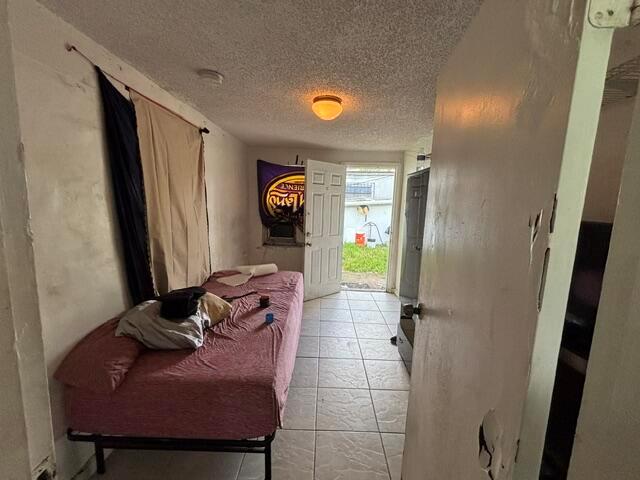 A small bedroom with a single bed, tile flooring, and an open door leading outside — 2451 NW 95th Terrace, Miami FL 33147, MIAMI, FL