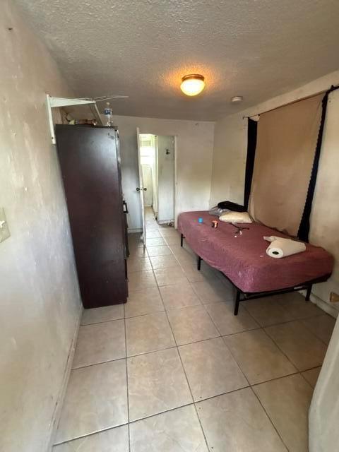 A small bedroom features a dark metal locker, a single bed, and light-colored floor tiles — 2451 NW 95th Terrace, Miami FL 33147, MIAMI, FL