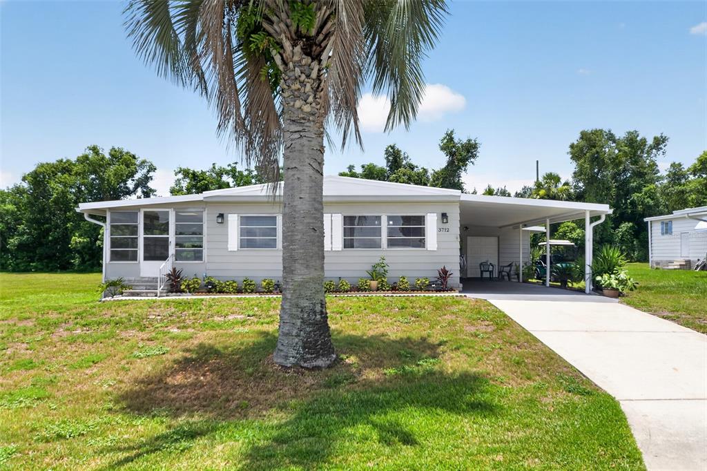 A single-story house with light gray siding, a palm tree, and a covered carport — 3712 S CITRUS CIRCLE UNIT GE, ZELLWOOD, FL
