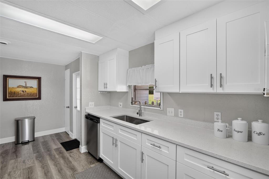 A kitchen features white cabinets, light countertops, a stainless steel sink, and wood-look flooring — 3712 S CITRUS CIRCLE UNIT GE, ZELLWOOD, FL