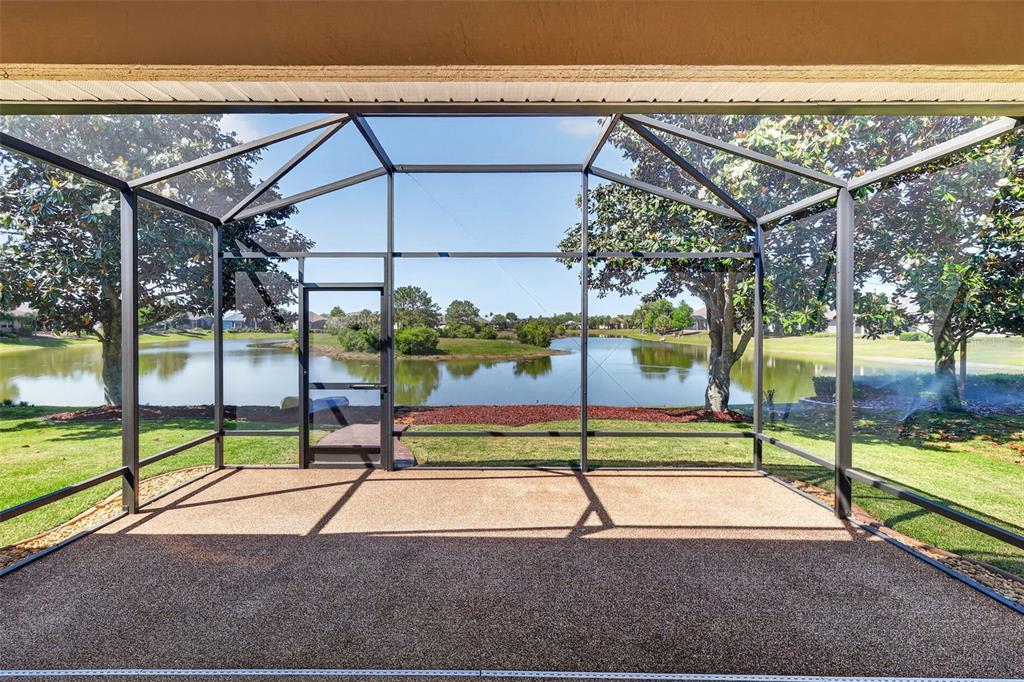 A backyard view of a pond with two kayaks resting on a red gravel area — 2359 WAKEFIELD WAY, MOUNT DORA, FL