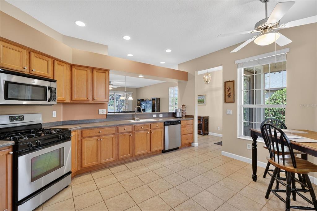 A kitchen with wood cabinets, stainless steel appliances, tile flooring, and an adjacent dining area — 2359 WAKEFIELD WAY, MOUNT DORA, FL