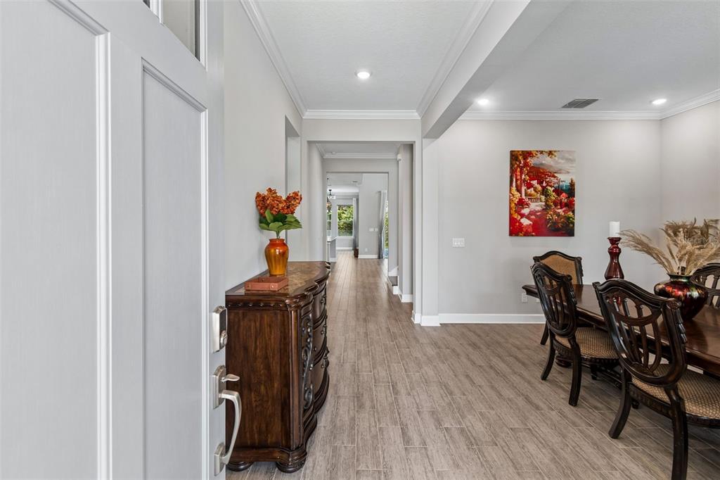 A foyer with wood-look tile flooring leads into a dining room and a long hallway — 747 CAJEPUT LOOP, TARPON SPRINGS, FL