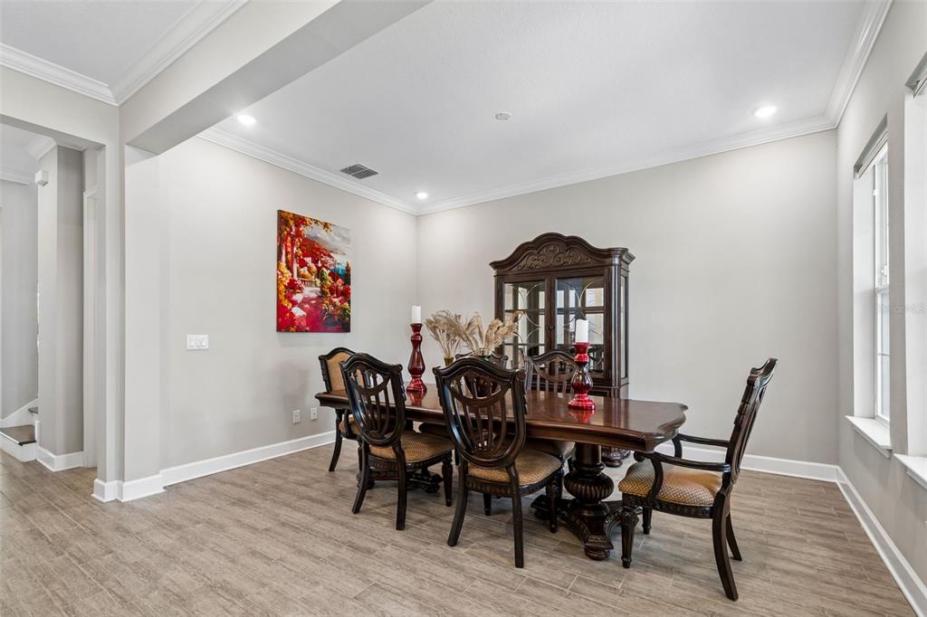 A dining room features a dark wood table with six chairs, a hutch, and tile flooring — 747 CAJEPUT LOOP, TARPON SPRINGS, FL