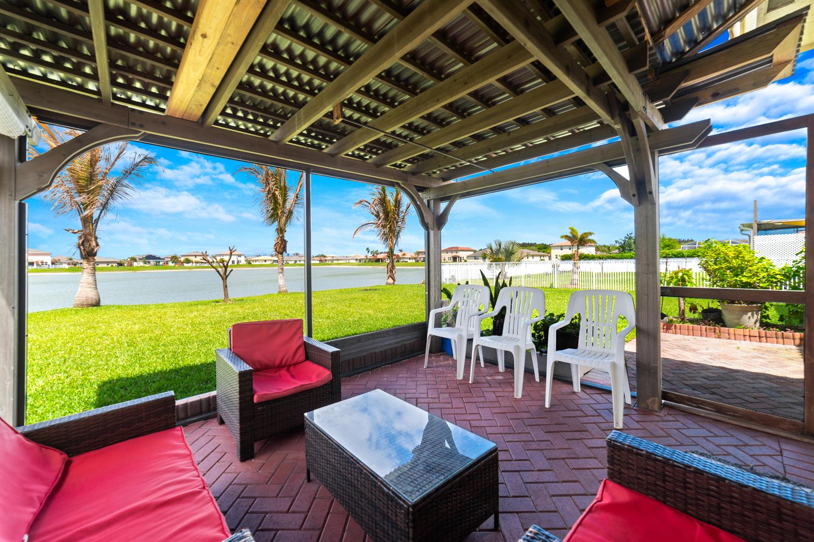 A screened-in patio with a brick floor, outdoor furniture, and a view of a lake — 879 Bent Creek Drive, Fort Pierce FL 34947, FORT PIERCE, FL
