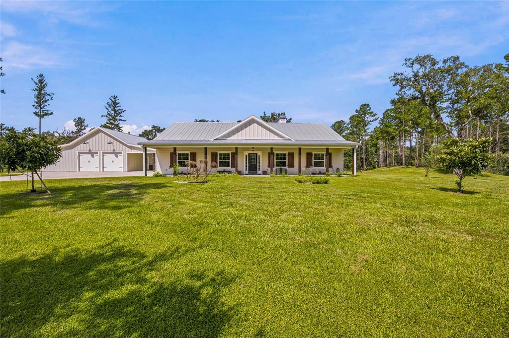 A single-story house with a metal roof and attached garage sits on a grassy lawn — 10080 SE 1ST STREET ROAD, SILVER SPRINGS, FL