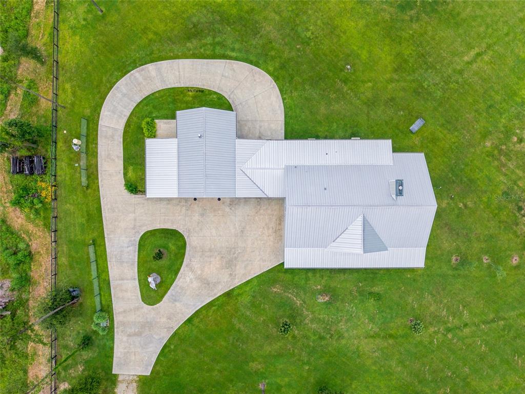 An aerial view shows a house with a metal roof and a large concrete driveway — 10080 SE 1ST STREET ROAD, SILVER SPRINGS, FL