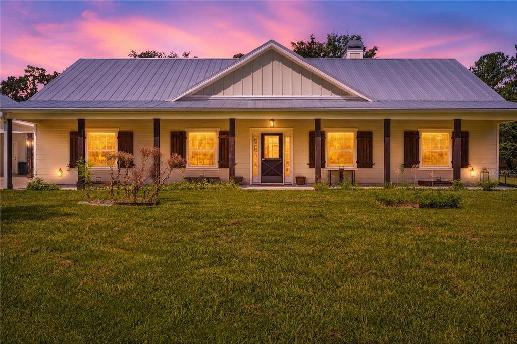 A single-story house with a metal roof and a covered front porch at sunset — 10080 SE 1ST STREET ROAD, SILVER SPRINGS, FL