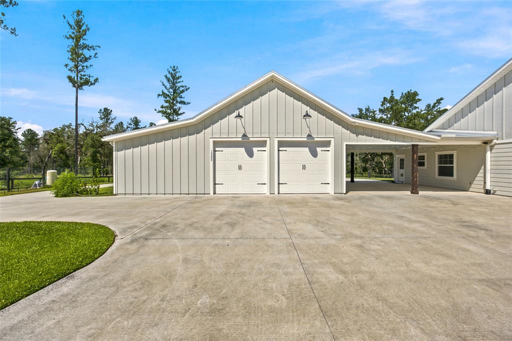 A light gray metal-sided garage with two white doors and an attached covered carport area — 10080 SE 1ST STREET ROAD, SILVER SPRINGS, FL