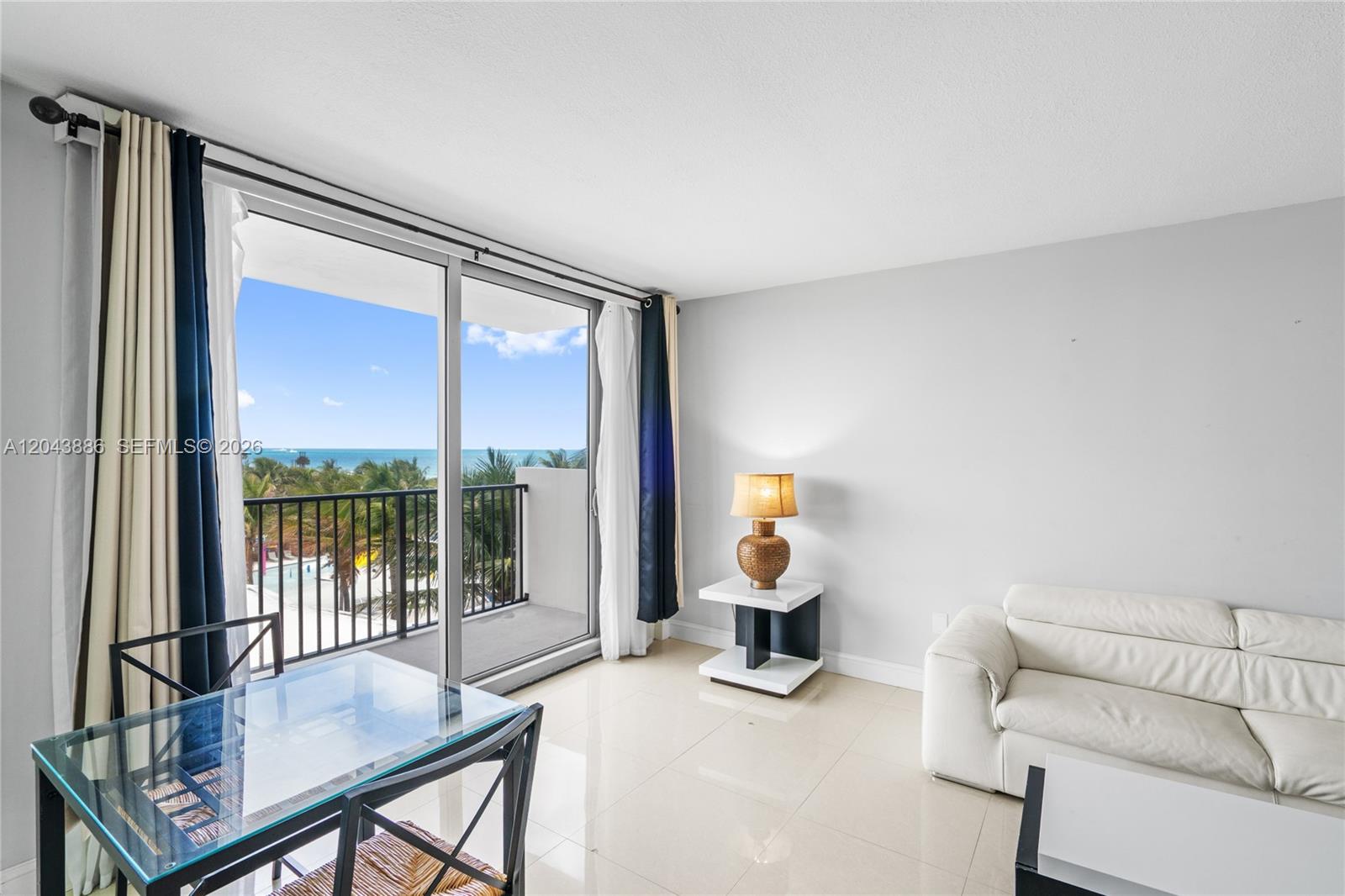 A living area features a white sofa, glass dining table, and balcony with ocean views — 9273 Collins Ave # 408, Surfside FL 33154, SURFSIDE, FL