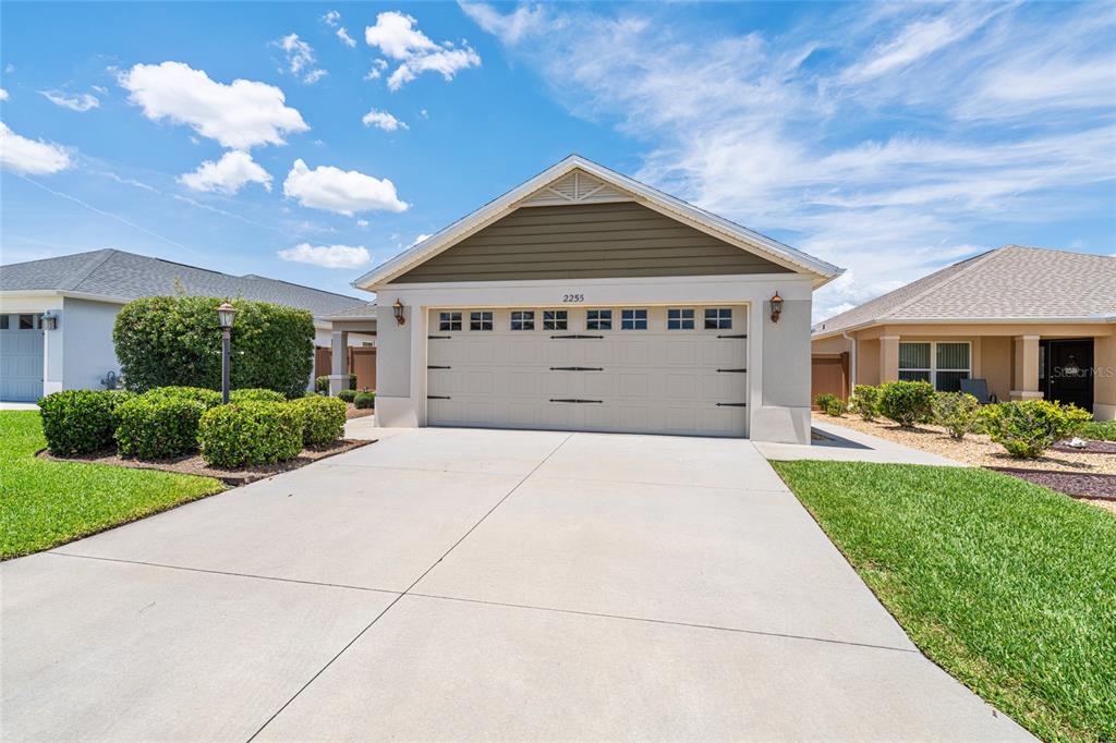 A single-story house with a beige garage door and a concrete driveway under a blue sky — 2255 PATRICIA PLACE, THE VILLAGES, FL