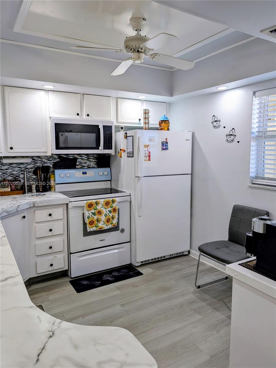 A kitchen features white cabinets, a white stove and refrigerator, and light wood-look flooring — 130 NE 26th Ave # 4010, Boynton Beach FL 33435, BOYNTON BEACH, FL