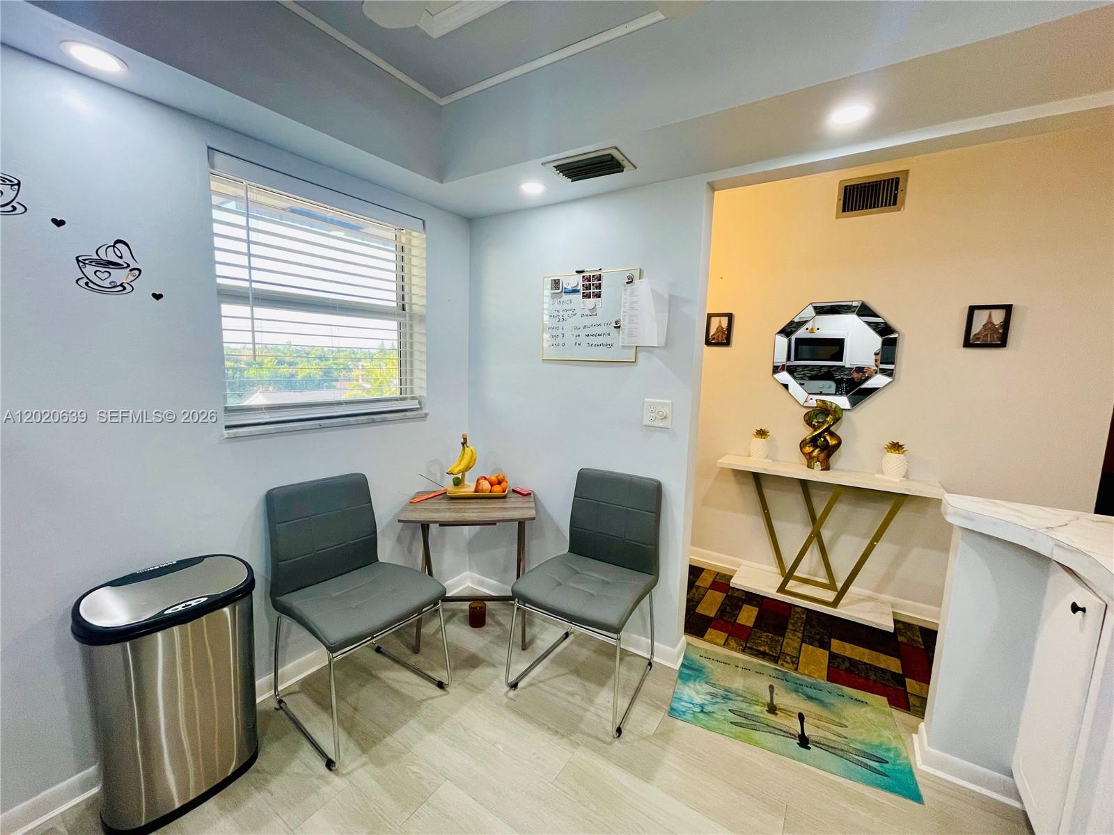 A small dining area features two gray chairs, a wooden table, and a wall-mounted whiteboard — 130 NE 26th Ave # 4010, Boynton Beach FL 33435, BOYNTON BEACH, FL