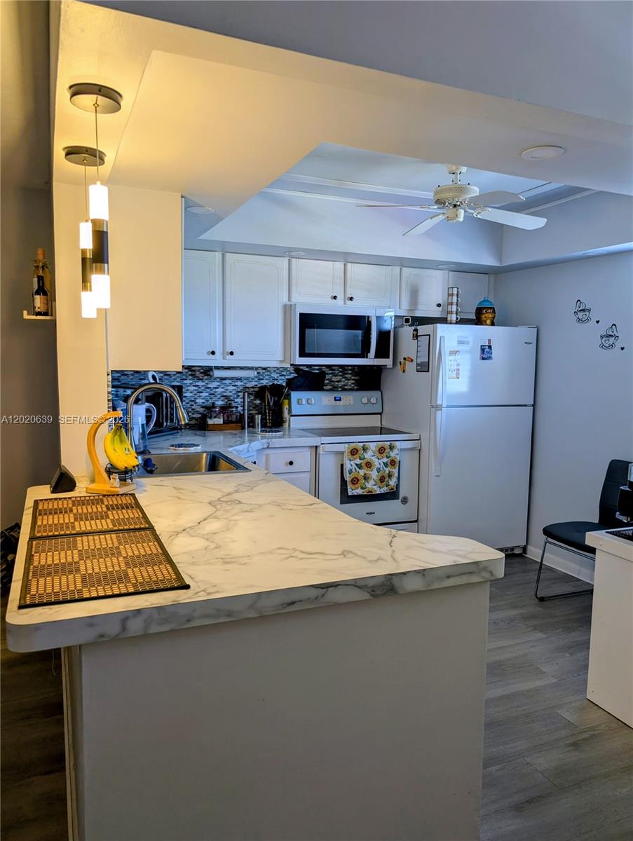 A kitchen features white cabinets, marble-patterned countertops, stainless steel appliances, and a ceiling fan — 130 NE 26th Ave # 4010, Boynton Beach FL 33435, BOYNTON BEACH, FL