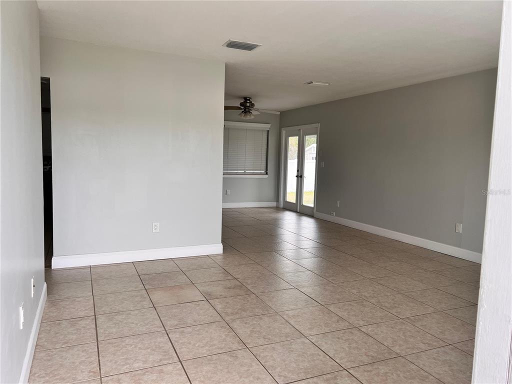An open-concept living area features light gray walls, beige tile flooring, and glass French doors — 1299 BIRCHCREST BOULEVARD, PORT CHARLOTTE, FL
