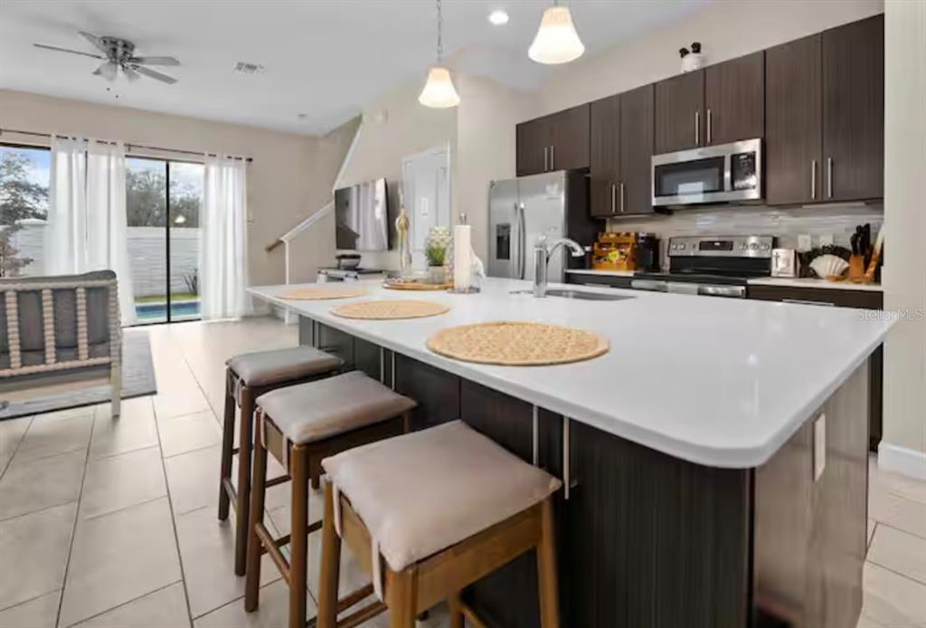 A modern kitchen features a large white island with bar seating and dark wood cabinetry — 192 VILLA DOMANI CIRCLE, DAVENPORT, FL