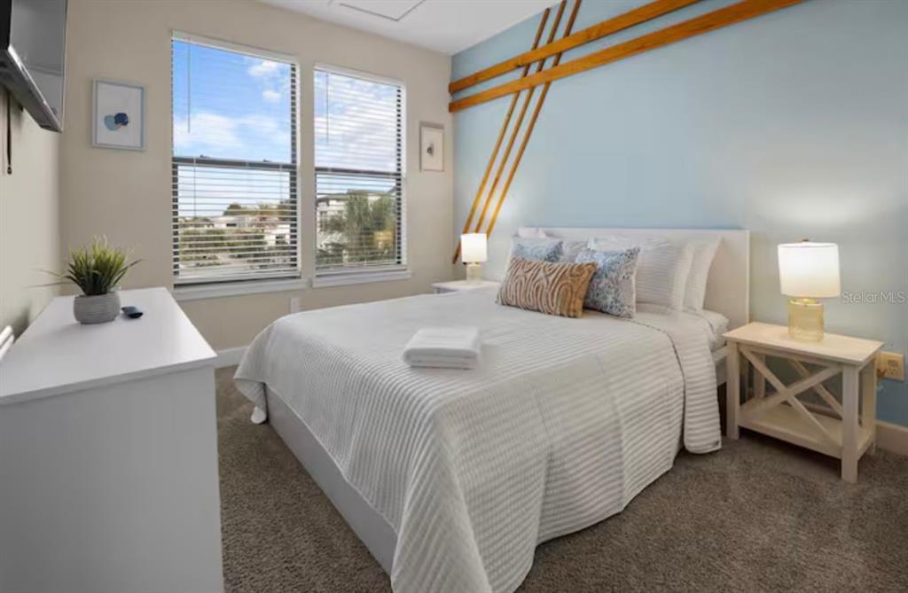 A bedroom features a bed with white bedding, a light blue wall with wood accents, and windows — 192 VILLA DOMANI CIRCLE, DAVENPORT, FL