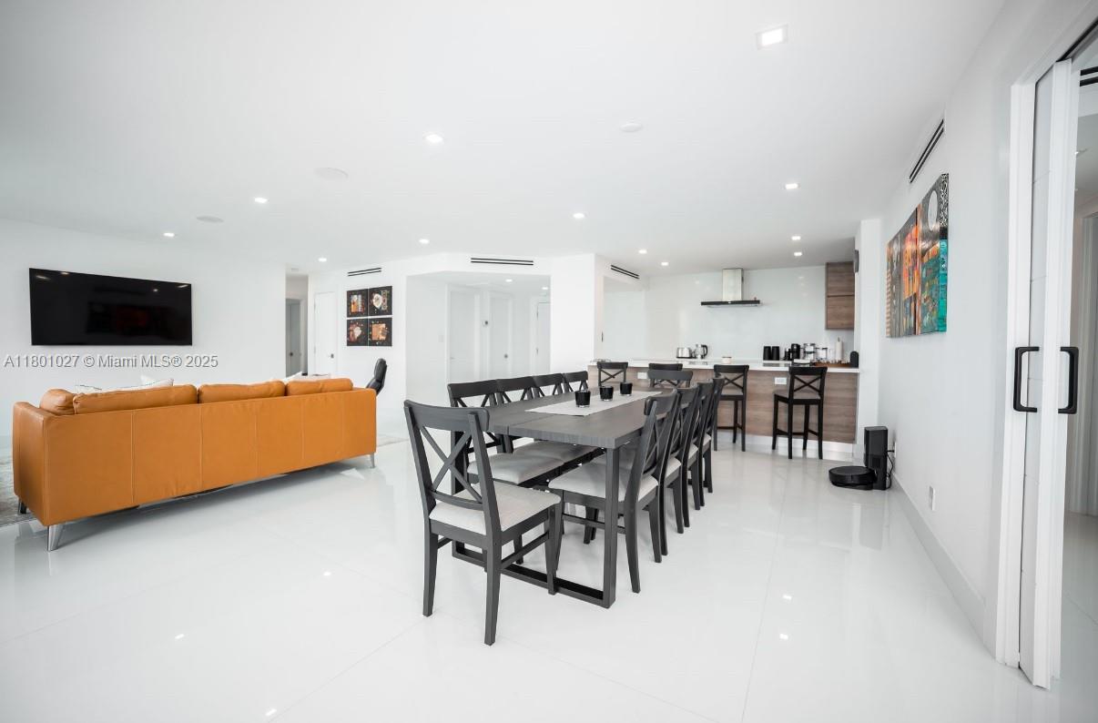 A modern open-concept living and dining area features white tile floors and an orange sofa — 5600 Collins Ave # 14K, Miami Beach FL 33140, MIAMI BEACH, FL