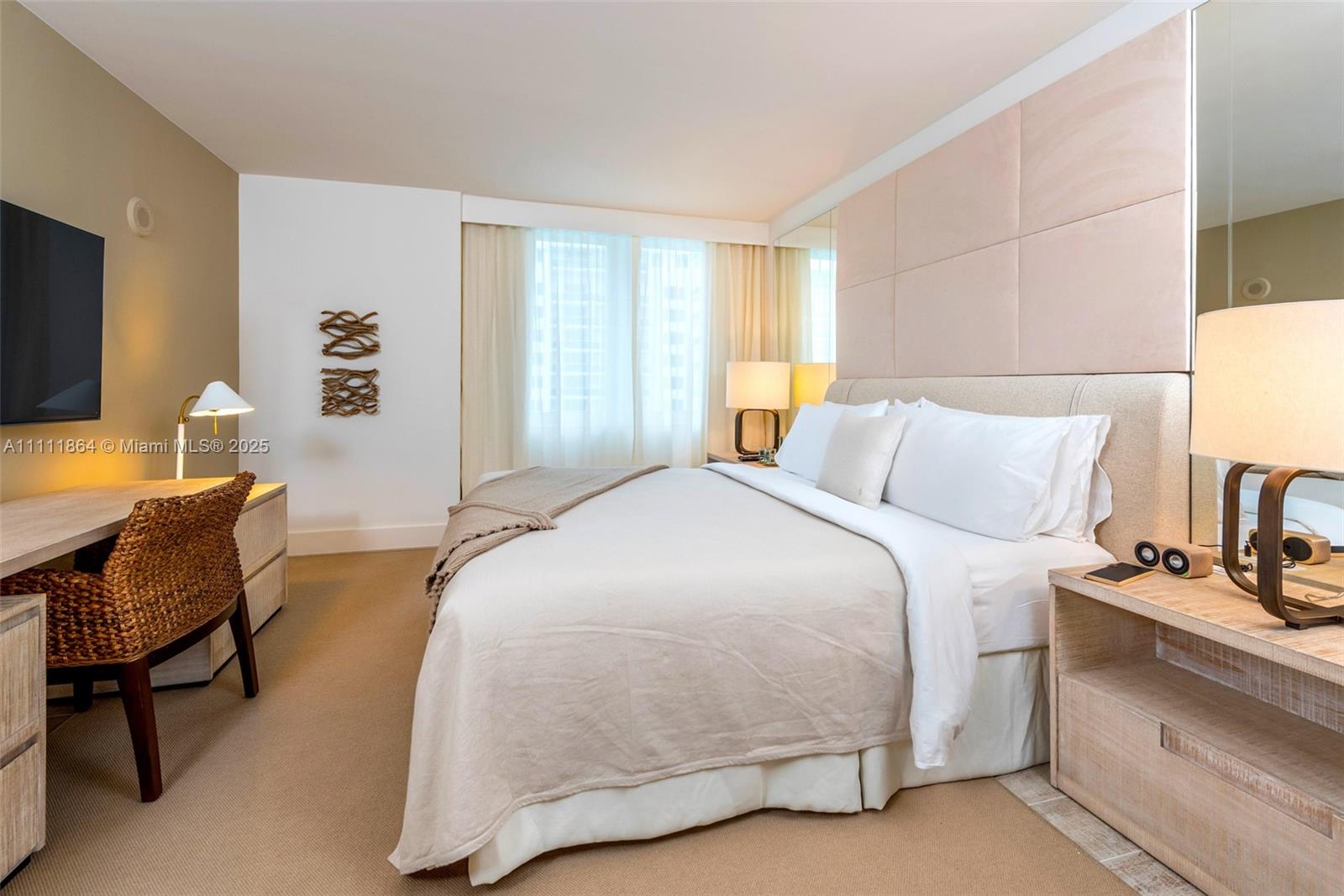 A bedroom features a bed, a desk with a woven chair, and neutral-toned decor — 102 24th St # 906, Miami Beach FL 33139, MIAMI BEACH, FL