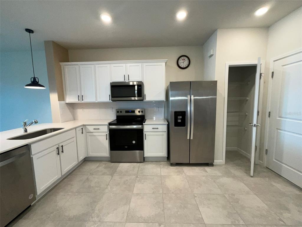 A kitchen with white cabinets, stainless steel appliances, tile flooring, and an open pantry — 2619 WINSOME WAY, DAVENPORT, FL