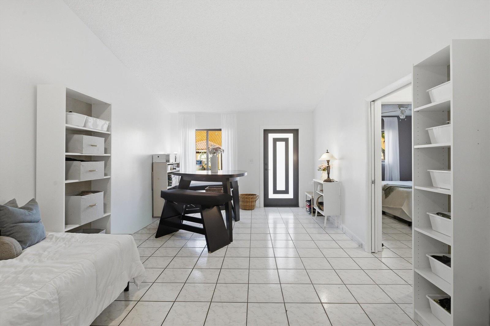 A bright living area features white tile floors, two tall shelving units, and a dining table — 5465 W 27th Lane, Hialeah FL 33016, HIALEAH, FL
