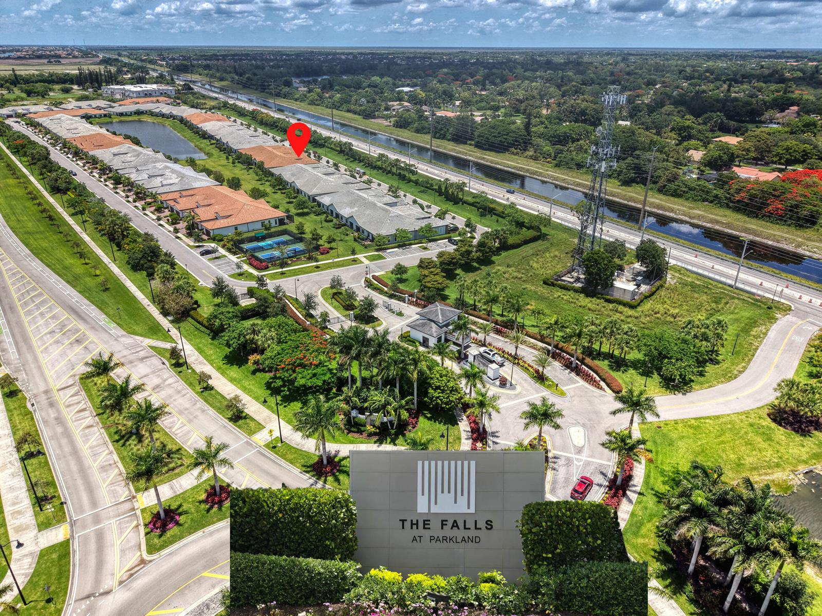 An aerial view shows a residential community with a gated entrance and a canal nearby — 7524 N Blue Spring Drive, Parkland FL 33067, PARKLAND, FL