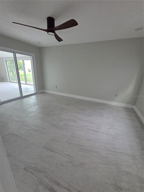 A bedroom with light gray walls, white tile flooring, a ceiling fan, and sliding glass doors — 1238 VALLEY FORGE BOULEVARD, SUN CITY CENTER, FL