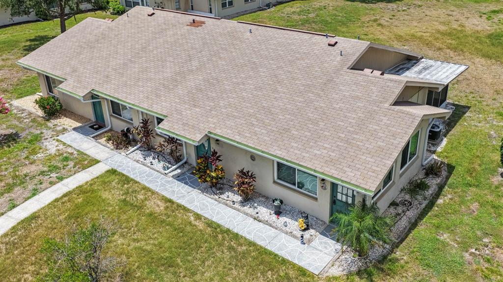 An aerial view shows the exterior of a single-story duplex with a shingled roof — 1906 CANTERBURY LANE UNIT 26, SUN CITY CENTER, FL