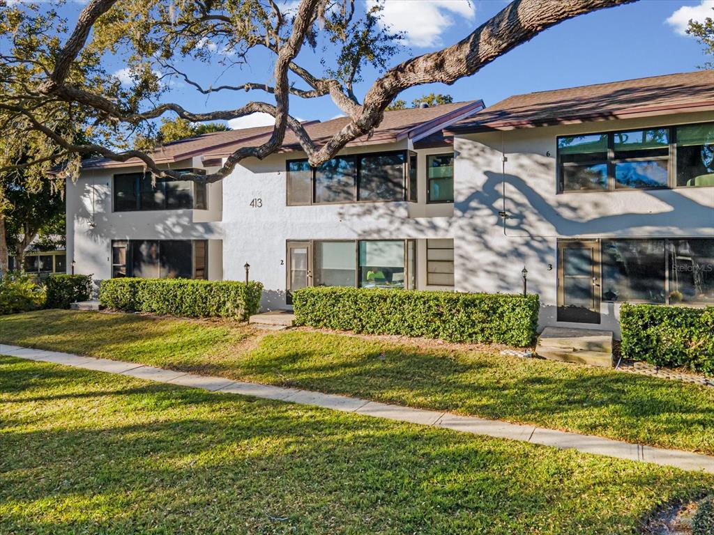 A two-story apartment building exterior features a white facade, dark-framed windows, and manicured hedges — 413 S BAYSHORE BOULEVARD UNIT 4, SAFETY HARBOR, FL