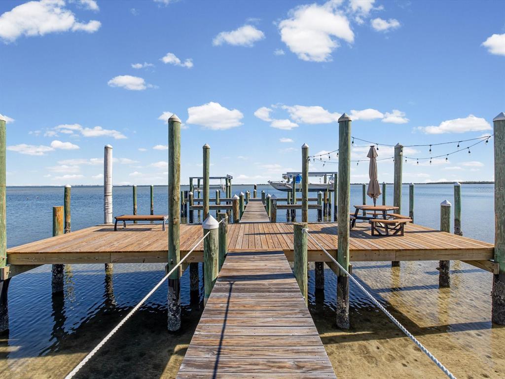A wooden dock with a bench, picnic table, and boat lift extends into the water — 413 S BAYSHORE BOULEVARD UNIT 4, SAFETY HARBOR, FL
