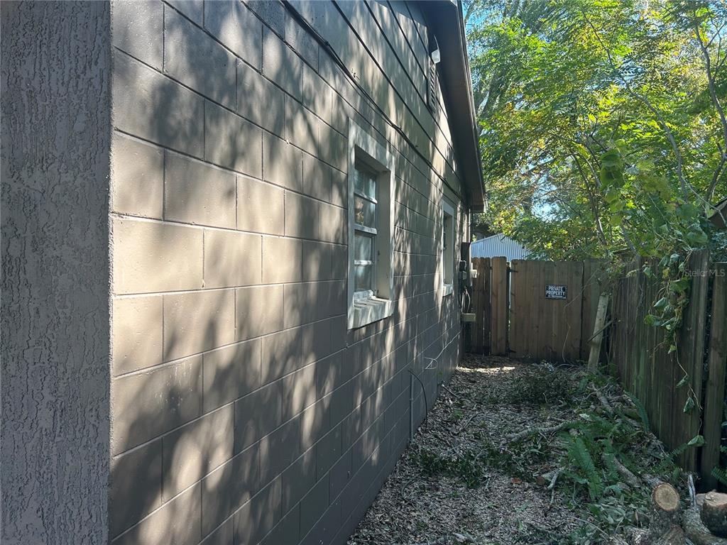 A side view of a brown concrete block house with a wooden fence and trees — 1121 ORANGE AVENUE, SANFORD, FL