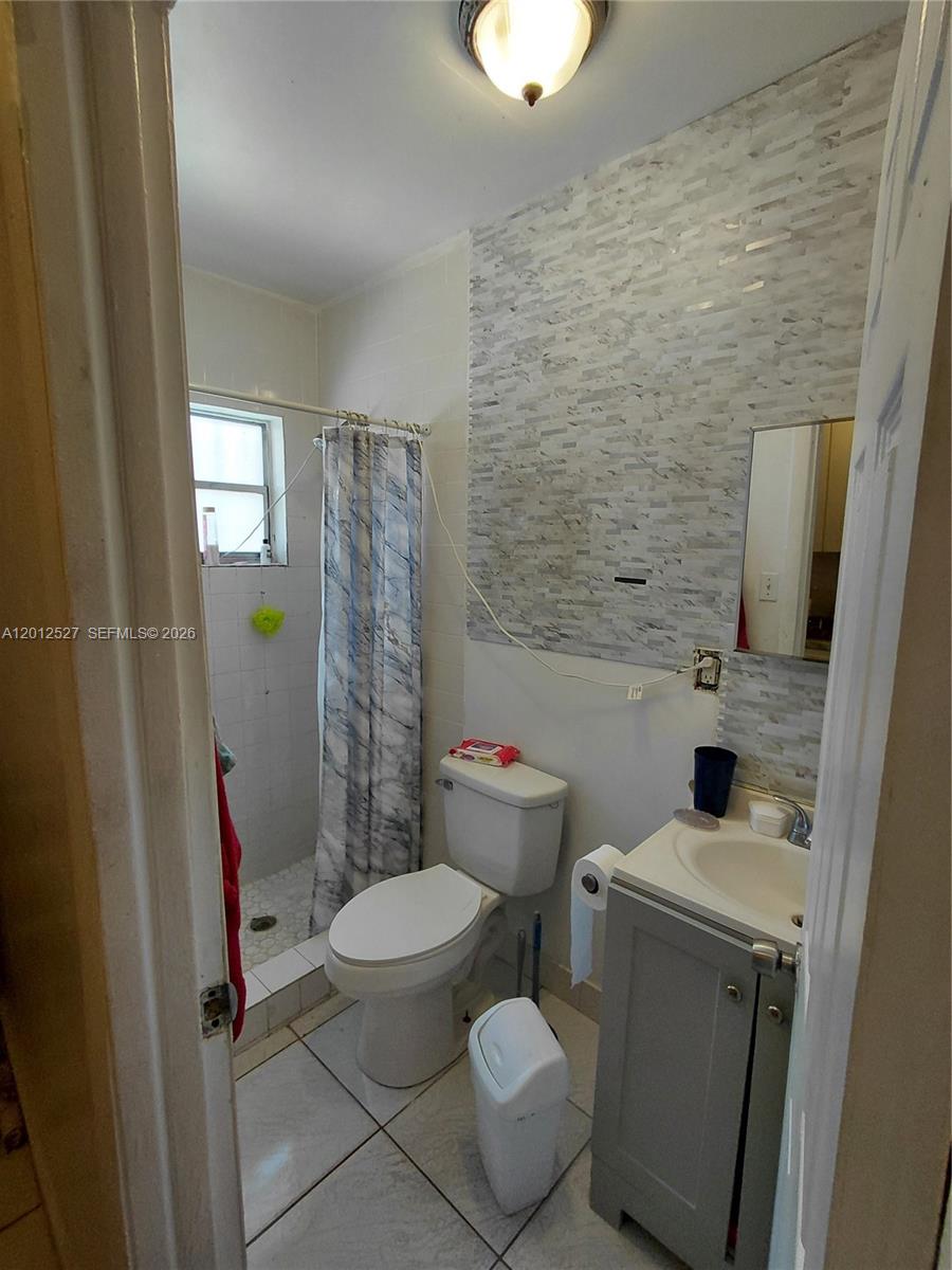 A small bathroom features a tiled shower, a toilet, and a gray vanity cabinet — 2140 NW 1st Ter, Miami FL 33125, MIAMI, FL