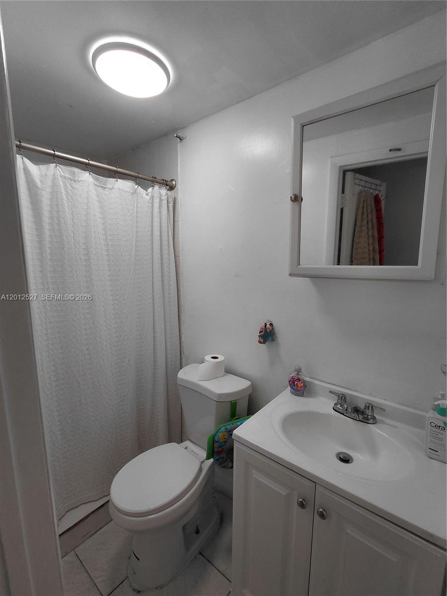 A small bathroom features a white vanity, a toilet, and a shower with a curtain — 2140 NW 1st Ter, Miami FL 33125, MIAMI, FL