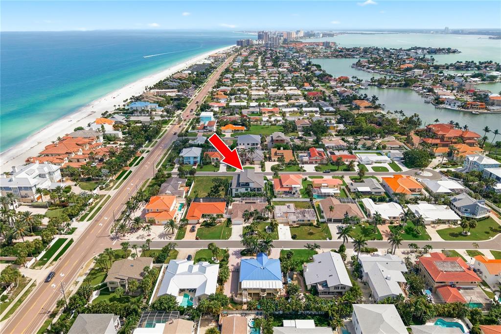 An aerial view shows a coastal neighborhood with houses, a beach, and a red arrow — 104 17TH STREET, BELLEAIR BEACH, FL