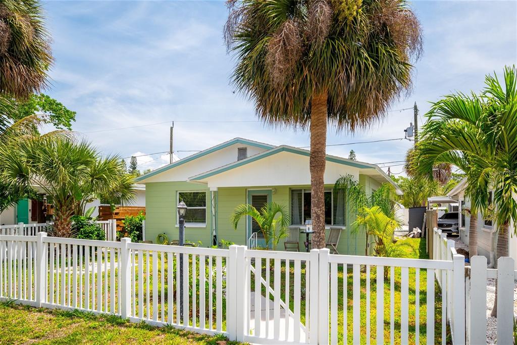 A light green house with a white picket fence and palm trees in the yard — 2920 57TH STREET S, GULFPORT, FL
