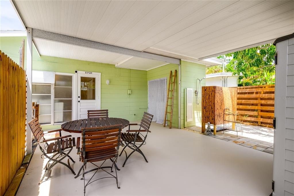 A covered patio features a round wooden table with chairs and an outdoor shower area — 2920 57TH STREET S, GULFPORT, FL