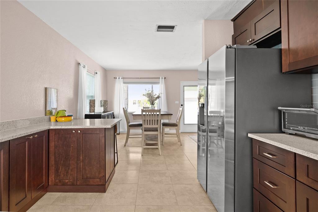 A kitchen with dark wood cabinets, granite countertops, and a dining area in the background — 2920 57TH STREET S, GULFPORT, FL