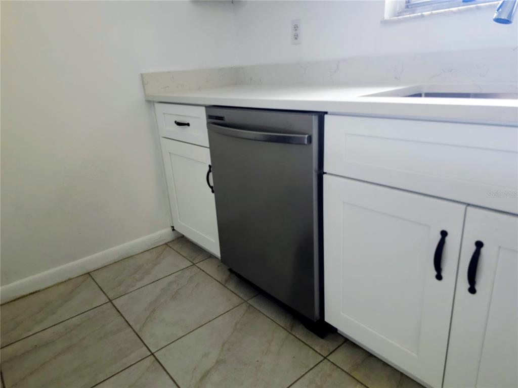 A kitchen features white cabinets, a stainless steel dishwasher, and light-colored countertops — 4008 BIANCA STREET, SEBRING, FL