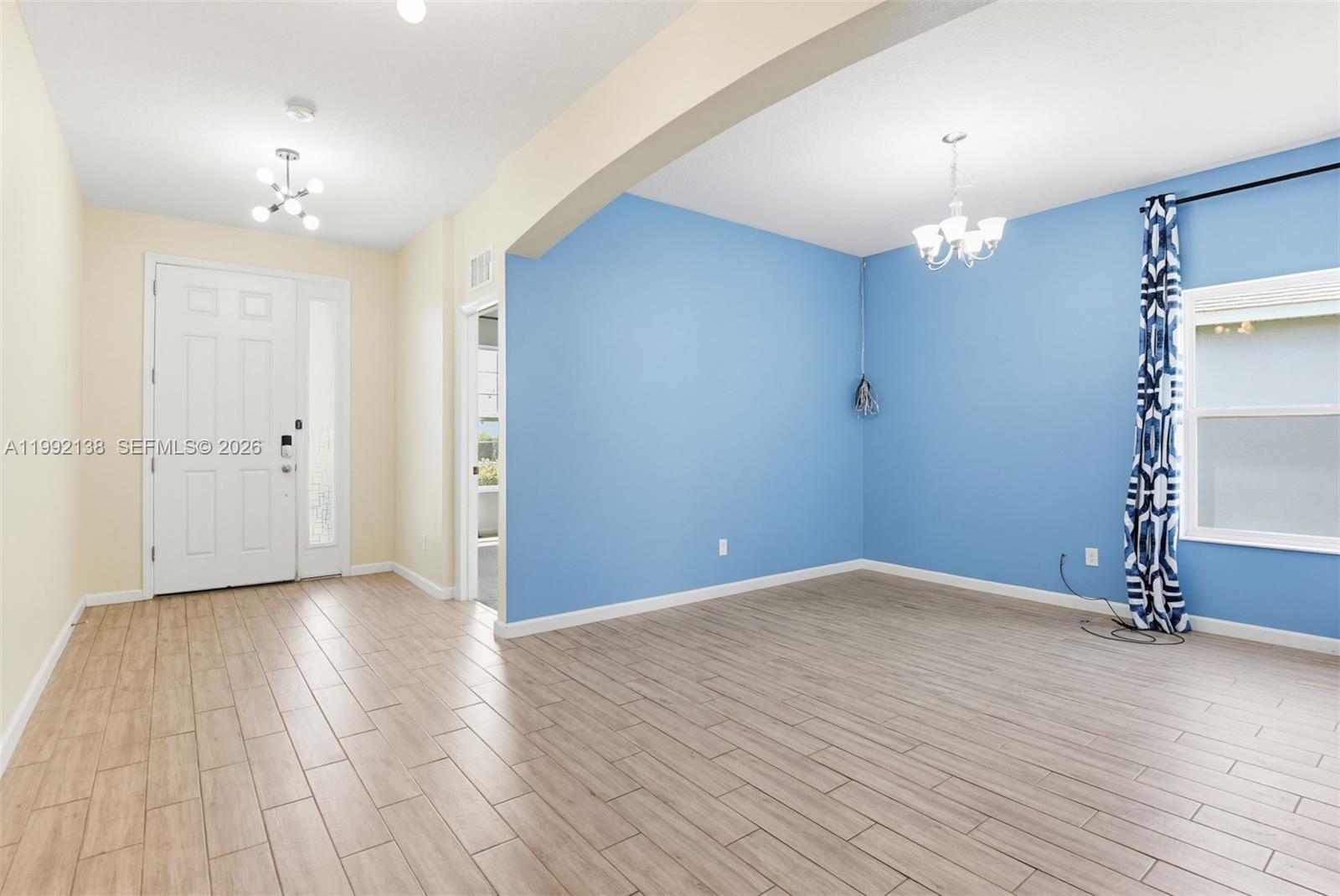 A room with light wood-look tile flooring, blue accent walls, and a white front door — 1034 CHELAN FALLS DR, Deland FL 32724, DELAND, FL