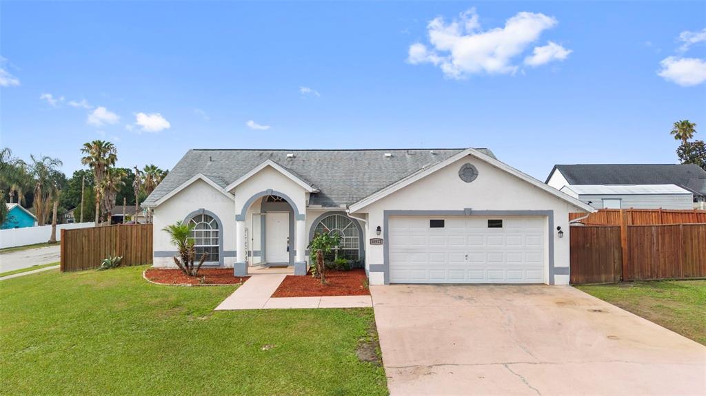 A single-story house with a white stucco exterior, a two-car garage, and a front lawn — 38912 CARR DRIVE, ZEPHYRHILLS, FL