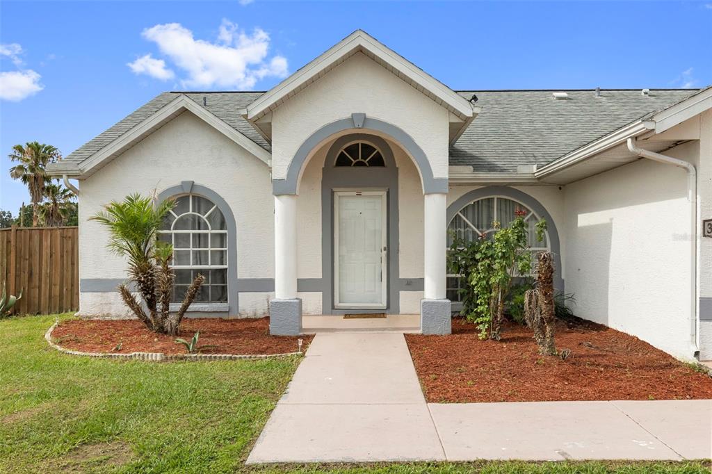 A single-story house with a white stucco facade, arched windows, and a covered front entryway — 38912 CARR DRIVE, ZEPHYRHILLS, FL